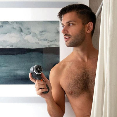 Male model stepping out of the shower holding the Clarisonic Mia Men Sonic Facial Cleansing Device With Charcoal Brush Head